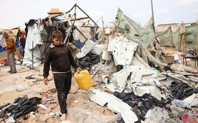 A Palestinian boy carries a container as he walks on debris at the site of an Israeli strike a day earlier on a camp for displaced people in Rafah in the southern Gaza Strip on May 28, 2024. (Eyad Baba/AFP)