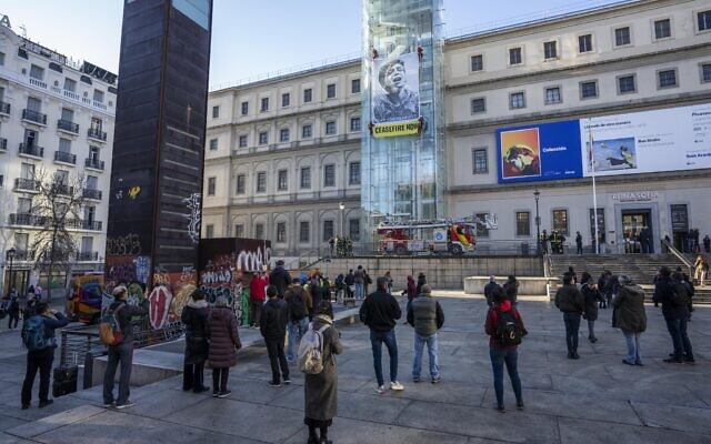 People watch as Greenpeace activists hang an illustration by US visual artist Shepard Fairey "Obey" outside the Reina Sofia museum with an image taken by Gazan photojournalist Belal Khaled, which shows a Palestinian child crying for help, Madrid, Spain Wednesday January 24, 2024.(AP Photo/Bernat Armangue) People watch as Greenpeace activists hang an illustration by US visual artist Shepard Fairey "Obey" outside the Reina Sofia museum with an image taken by Gazan photojournalist Belal Khaled, which shows a Palestinian child crying for help, Madrid, Spain Wednesday January 24, 2024.(AP Photo/Bernat Armangue)
