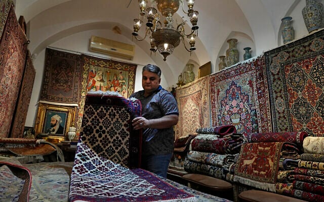 Iranian carpet shop owner Ali Faez works at his shop at the traditional bazaar of the city of Kashan, about 152 miles (245 km) south of the capital Tehran, Iran, April 30, 2024. (AP Photo/Vahid Salemi)