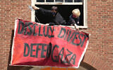 Activists hang a placard from a window of an upper floor of a building at Rhode Island School of Design, Tuesday, May 7, 2024, in Providence, Rhode Island, as students and supporters, who have taken over a portion of the building, are demanding that the school condemn Israel's war effort in Gaza, and that the school divest from investments that benefit Israel. (AP Photo/Steven Senne, File)