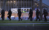A line of police in riot gear walk past police dismantling pro-Palestinian encampment at MIT, before dawn Friday, May 10, 2024, in Cambridge, Mass. (AP Photo/Josh Reynolds)