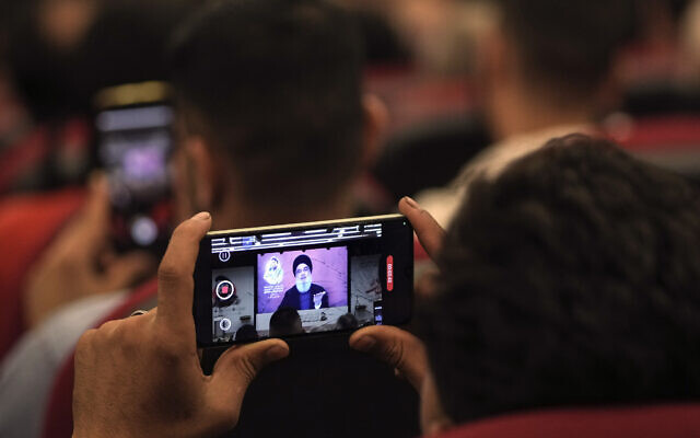 A supporter films a speech by Hezbollah leader Hassan Nasrallah with a mobile phone as speaking via a video link, in the southern suburbs of Beirut, Lebanon, May 13, 2024. (AP Photo/Hassan Ammar)