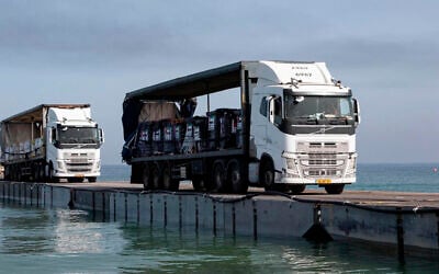Trucks loaded with humanitarian aid from the United Arab Emirates and the United States Agency for International Development cross the Trident Pier before entering the beach in Gaza, May 17, 2024. (Staff Sgt. Malcolm Cohens-Ashley/US Army Central via AP)
