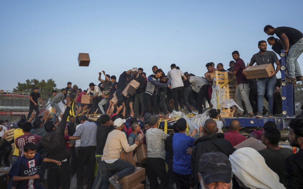 Palestinians storm trucks loaded with aid brought in through a new US-built pier, in the central Gaza Strip, May 18, 2024. (AP Photo/Abdel Kareem Hana)