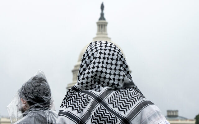 A man wearing a keffiyeh looks at the US Capitol during a pro-Palestinian, anti-Israel rally on May 18, 2024, on the National Mall in Washington. (AP Photo/Jacquelyn Martin)