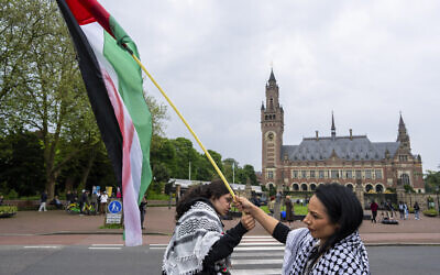 Two demonstrators wave the Palestinian flag outside the Peace Palace, rear, housing the International Court of Justice, or World Court, in The Hague, Netherlands,May 24, 2024. (AP/Peter Dejong)