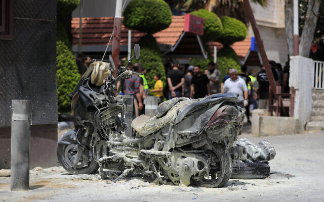 A charred motorcycle is seen after an Israeli strike outside Salah Ghandour Hospital, background, in Bint Jbeil town, south Lebanon, May 27, 2024. (AP Photo/Mohammad Zaatari)