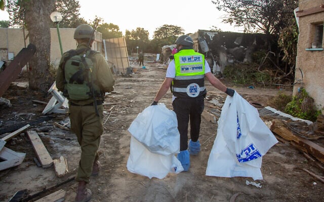 ZAKA volunteers walk through the destruction caused by Hamas terrorists in Kibbutz Kfar Aza, as they collect dead bodies, October 15, 2023. (Edi Israel/ Flash90) ZAKA volunteers walk through the destruction caused by Hamas terrorists in Kibbutz Kfar Aza, as they collect dead bodies, October 15, 2023. (Edi Israel/ Flash90)