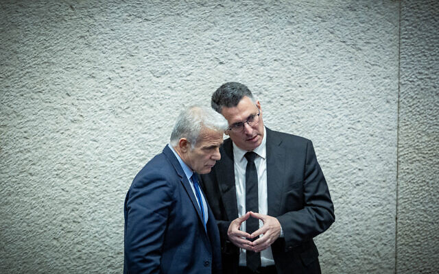 Opposition Leader Yair Lapid speaks with New Hope chairman Gideon Sa'ar during a vote on the state budget at the assembly hall of the Knesset, March 13, 2024. (Yonatan Sindel/Flash90)