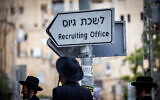 Ultra-Orthodox Jewish men near a sign reading 'army recruitment office' during a protest against the drafting of Haredim to the military, in Jerusalem, May 1, 2024. (Yonatan Sindel/Flash90)
