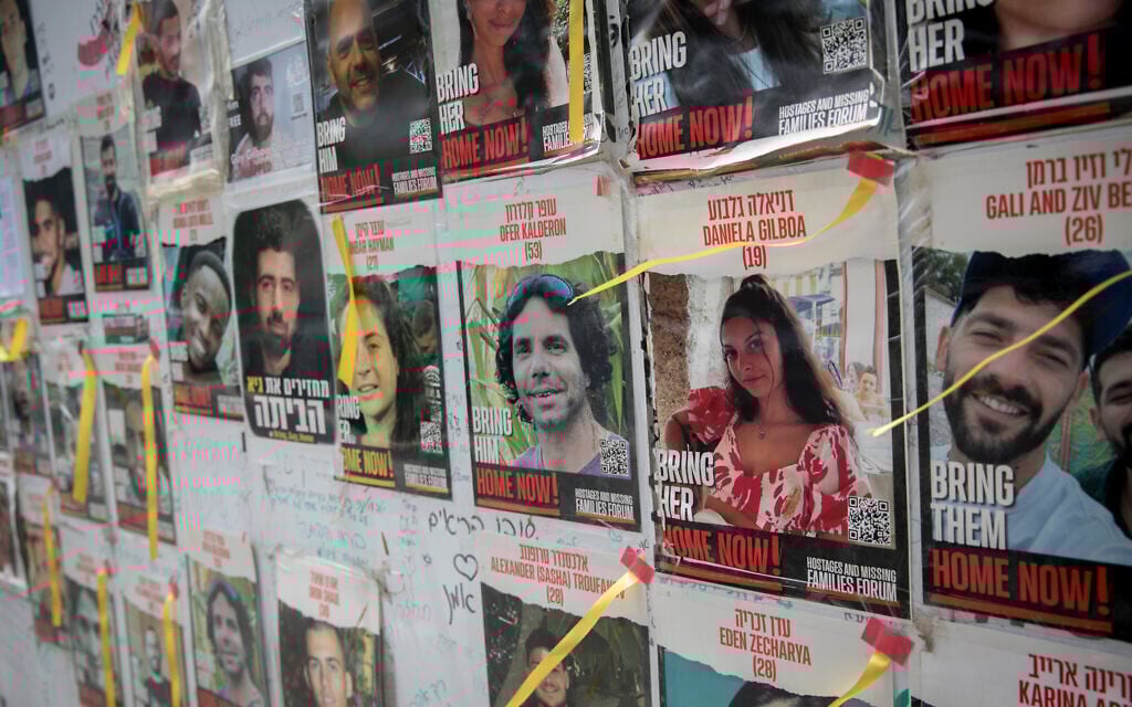 People walk by photographs of Israelis still held hostage by Hamas terrorists in Gaza, May 28, 2024. (Miriam Alster/FLASH90)