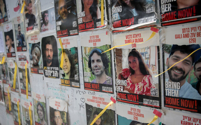 People walk by photographs of Israelis still held hostage by Hamas terrorists in Gaza, May 28, 2024. (Miriam Alster/FLASH90)