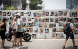 People in Tel Aviv walk by photographs of hostages held in Gaza, on May 28, 2024. (Miriam Alster/Flash90)