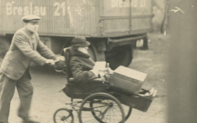 A man pushes an elderly woman in a wheelchair as she carries a suitcase on her legs. In the back can be seen a truck from the shipping company sent to pick up the luggage. The wall projection on his right shields the photographer from being seen. Breslau, Silesia, November 21, 1941. (Courtesy of the Landesverband Sachsen der Jüdischen Gemeinden in Dresden)