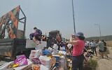 Activists from the Standing Together organization help reload cartons of humanitarian aid destined for Gaza thrown off a truck by extremists opposing the supply of aid to Gaza at the Tarqumiyah Crossing in the West Bank, May 19, 2024. (Courtesy Standing Together)