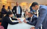 Ariel Kandel stands and listens to a prospective immigrant speaking with Jerusalem Mayor Moshe Lion, wearing a tie, at an aliyah fair in Paris, France on May 19, 2024. (Qualita)