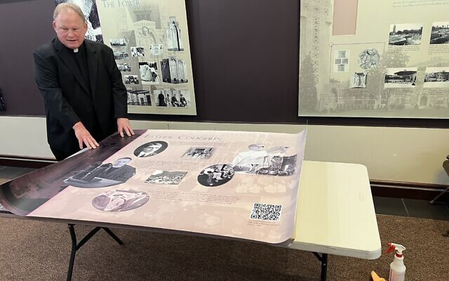 Rev. John Bettin, head pastor at the National Shrine of the Little Flower Catholic parish, prepares to mount a revised version of the church's history of its antisemitic founder Father Charles Coughlin, Royal Oak, Michigan, Novemver 7, 2023. The new version includes a QR code for visitors to learn more about Coughlin's antisemitism. (Courtesy of Levi Smith via JTA)