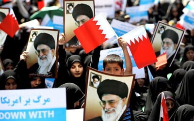Iranian demonstrators hold up portraits of the Islamic Republic's supreme leader, Ayatollah Ali Khamenei, and wave Bahraini flags during a protest after the Friday noon prayer in Tehran on May 18, 2012, held in response to a government call to protest a plan to unite Bahrain with Saudi Arabia that Tehran has said is a US plot. (Atta KENARE / AFP)