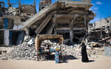 Illustrative: A displaced Palestinian man displays food items for sale in front of destroyed buildings in Khan Younis in the southern Gaza Strip, May 24, 2024. (Eyad Baba/AFP)
