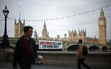 A banner reading 'Keir Starmer: Will Labour Stop Arming Israel?' is hung over the side of Westminster Bridge, in front of the Palace of Westminster, in London on June 3, 2024. (Henry Nicholls/AFP)