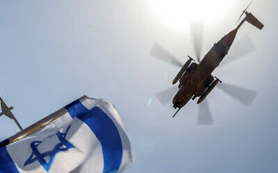 An Israel Air Force CH-53 Sea Stallion military helicopter flies over as people gather with Israeli national flags outside Sheba Tel Hashomer Medical Centre in Ramat Gan on June 8, 2024, where Israeli hostages were transferred after being rescued from captivity in the Gaza Strip since the October 7 attacks. (Jack Guez / AFP)