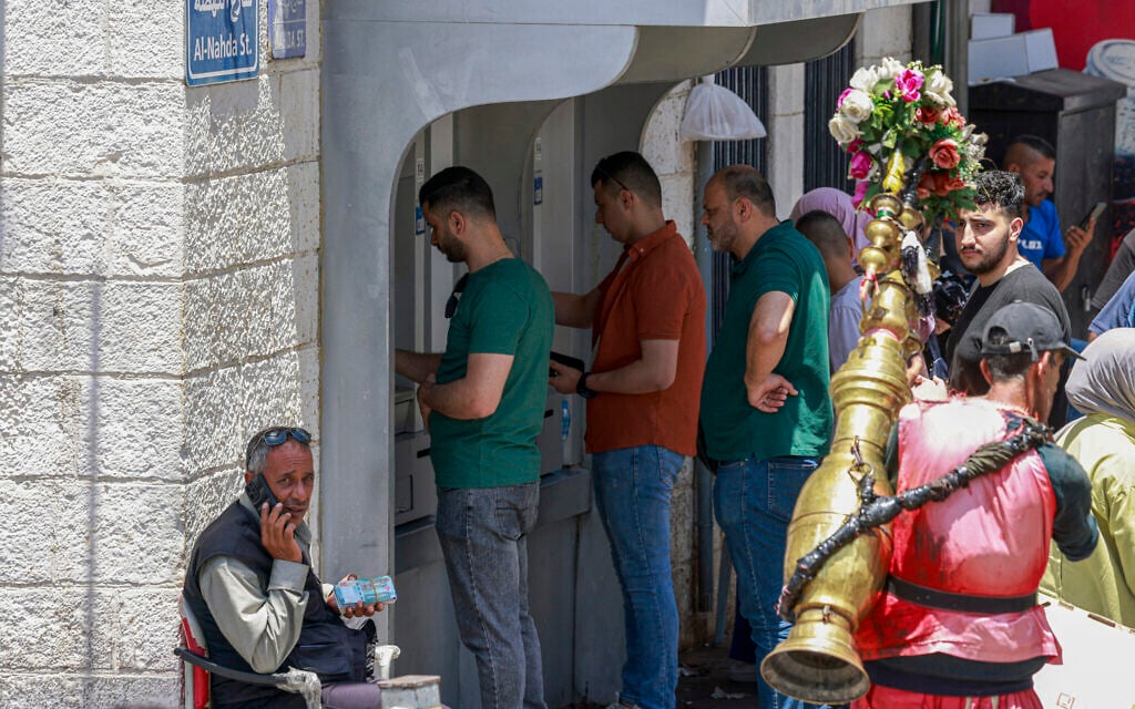 Palestinians wait in line to withdraw money from an ATM in the main market in Ramallah city in the West Bank on June 9, 2024. (Jaafar ASHTIYEH / AFP)