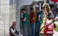 Palestinians wait in line to withdraw money from an ATM in the main market in Ramallah city in the West Bank on June 9, 2024. (Jaafar ASHTIYEH / AFP)