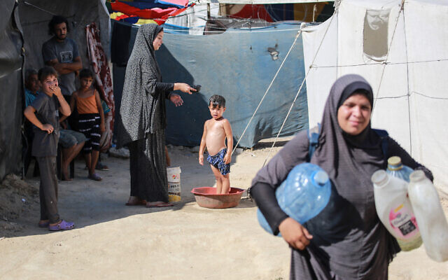 A Palestinian woman washes a child at a camp for displaced people in Deir al-Balah, in the central Gaza Strip, on June 11, 2024. (Bashar TALEB / AFP) A Palestinian woman washes a child at a camp for displaced people in Deir al-Balah, in the central Gaza Strip, on June 11, 2024. (Bashar TALEB / AFP)