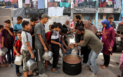 Children queue with pots to receive food aid from a kitchen at the Abu Zeitun school run by the UN Relief and Works Agency for Palestine Refugees (UNRWA) in Jabaliya in the northern Gaza Strip, June 13, 2024. (Omar Al-Qattaa/AFP)