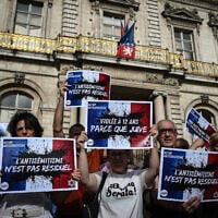 Protesters hold placards decrying antisemitism as they gather to condemn the antisemitic gang rape of a 12-year-old girl, during a rally in Lyon, France, June 19, 2024. (Jean-Philippe Ksiazek/AFP)