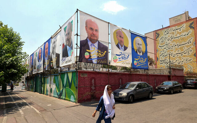 Illustrative: A woman walks past electoral posters in Tehran on June 20, 2024, ahead of the June 28 election to replace President Ebrahim Raisi, who was killed in a helicopter crash. (Atta Kenare / AFP) Illustrative: A woman walks past electoral posters in Tehran on June 20, 2024, ahead of the June 28 election to replace President Ebrahim Raisi, who was killed in a helicopter crash. (Atta Kenare / AFP)