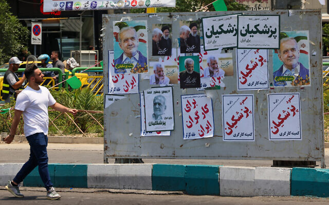 Illustrative: A man walks past electoral posters in Tehran on June 20, 2024, ahead of the June 28 election to replace President Ebrahim Raisi, who was killed in a helicopter crash. (Atta Kenare / AFP) Illustrative: A man walks past electoral posters in Tehran on June 20, 2024, ahead of the June 28 election to replace President Ebrahim Raisi, who was killed in a helicopter crash. (Atta Kenare / AFP)