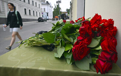 A woman walks past flowers lying in front of the representative office of Dagestan in Moscow on June 24, 2024, following terrorist attacks in Dagestan. (Alexander NEMENOV / AFP)