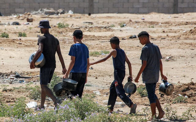 A man and three boys walk with pots on their way to a charity kitchen to collect food, northwest of Rafah in the southern Gaza Strip on June 24, 2024. (Bashar Taleb/AFP) A man and three boys walk with pots on their way to a charity kitchen to collect food, northwest of Rafah in the southern Gaza Strip on June 24, 2024. (Bashar Taleb/AFP)