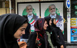 Women walk past election posters for Iranian reformist presidential candidate Massoud Pezeshkian along a street in Tehran on June 26, 2024 ahead of the vote. (RAHEB HOMAVANDI / AFP)