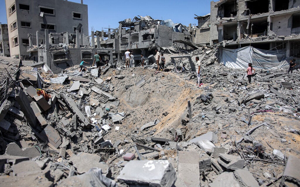 People gather around an impact crater in the aftermath of Israeli bombardment in the Sabra neighbourhood in the south of Gaza City on June 27, 2024. (Omar AL-QATTAA / AFP)