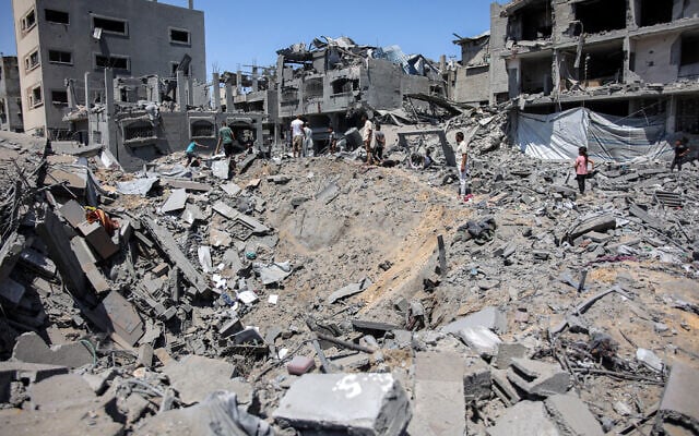 People gather around an impact crater in the aftermath of Israeli bombardment in the Sabra neighbourhood in the south of Gaza City on June 27, 2024. (Omar AL-QATTAA / AFP)