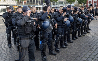 German police officers take off their caps in Mannheim Germany, after learning that a police officer, who was stabbed two days ago there, died on June 2, 2024. (AP Photo/ Michael Probst)
