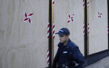 A forensic officer walks past boarded windows at the US consulate as police investigate the vandalism in Sydney, June 10, 2024. (AP Photo/Rick Rycroft)