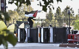 A student protester waves a Palestinian flag atop turned over utility carts at California State University, Los Angeles on Wednesday, June 12, 2024. (Keith Birmingham/The Orange County Register via AP)