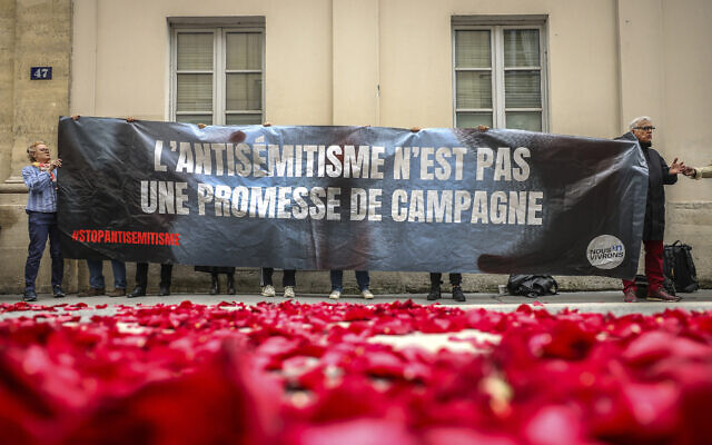 Illustrative: Protesters hoist a banner reading 'Antisemitism is not a campaign promise,' at the entrance to a press conference where leftist French leaders announced they were forming an alliance called the New Popular Front, in Paris, France, June 14, 2024. (AP Photo/Thomas Padilla) Illustrative: Protesters hoist a banner reading 'Antisemitism is not a campaign promise,' at the entrance to a press conference where leftist French leaders announced they were forming an alliance called the New Popular Front, in Paris, France, June 14, 2024. (AP Photo/Thomas Padilla)