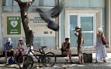 Tourists sit under a tree for shade amid hot weather at Eleftherias, Liberty, square in central capital Nicosia, Cyprus, on Friday, June 14, 2024. (AP/Petros Karadjias)