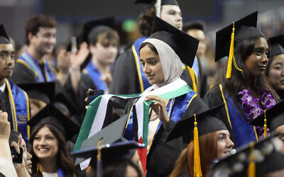 A UCLA graduating student holds a Palestinian flag during the commencement ceremony inside Pauley Pavilion on the UCLA campus, in Los Angeles, June 14, 2024. (AP/Damian Dovarganes)