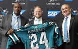Ryan Warsofsky, middle, holds up a jersey between San Jose Sharks general manager Mike Grier, left, and president Jonathan Becher at a news conference introducing Warsofsky as the NHL hockey head coach of the Sharks in San Jose, California, June 17, 2024. (Jeff Chiu/AP)