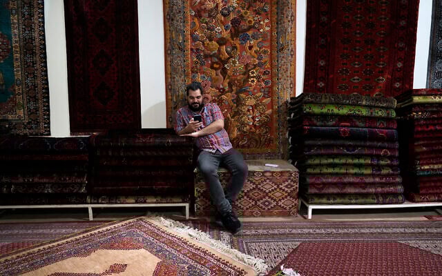 A salesman on his cellphone at a carpet shop in the old main bazaar of Tehran, Iran, June 13, 2024 (AP/Vahid Salemi) A salesman on his cellphone at a carpet shop in the old main bazaar of Tehran, Iran, June 13, 2024 (AP/Vahid Salemi)