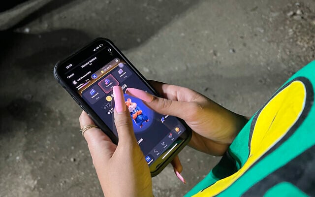 A woman plays Hamster Combat game on a cell phone in Tehran, Iran, June 23, 2024 (AP Photo/Vahid Salemi)