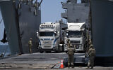 US Army soldiers gesture as trucks loaded with humanitarian aid arrive at the US-built floating pier Trident before reaching the beach on the coast of the Gaza Strip, June 25, 2024. (AP Photo/Leo Correa)