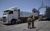 US Army soldiers stand next to trucks arriving loaded with humanitarian aid at the US-built floating pier Trident before reaching the beach on the coast of the Gaza Strip, June 25, 2024. (AP Photo/Leo Correa)