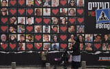 A woman and her children walk past a wall with photographs of hostages who were kidnapped during the October 7, 2023, Hamas cross-border attack in Israel, seen in Jerusalem, February 26, 2024. (Leo Correa/AP)