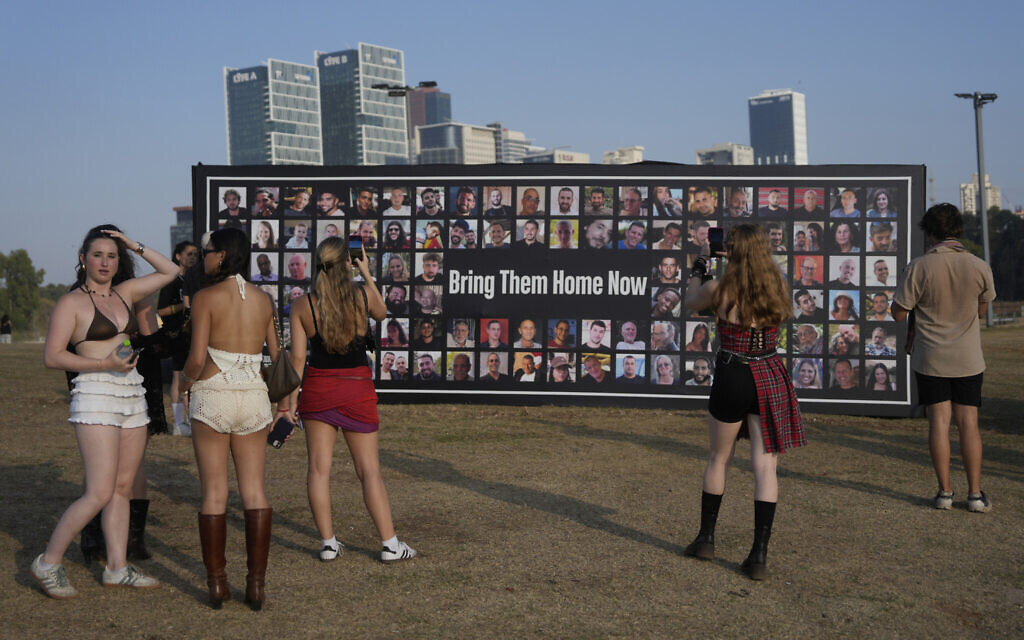 People pause at a picture display of hostages held by Hamas in the Gaza Strip, at the Nova Healing Concert in Tel Aviv, Israel, on Thursday, June 27, 2024.  (AP Photo/Ohad Zwigenberg)